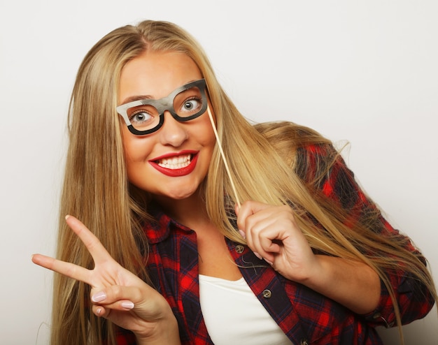 Party image.Young woman holding a party glasses. Over white wall.