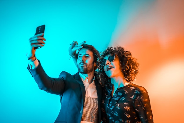 Party lifestyle a Caucasian couple taking a selfie at a party with orange and blue lights