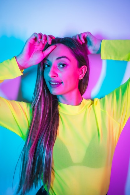 Stile di vita di festa in una discoteca con luci al neon blu rosa ritratto di una giovane ragazza bionda caucasica che si diverte con una maglietta gialla