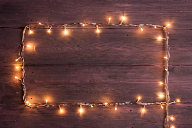 Party lights decoration Wooden background with christmas lights garland frame with copy space for a text