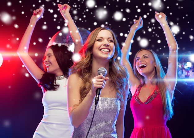 party, new year, celebration, friends, bachelorette party, birthday concept - three women in evening dresses dancing and singing karaoke