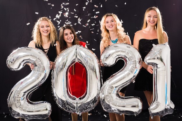 Party, people and new year holidays concept - cheerful young women celebrating new years eve 2021