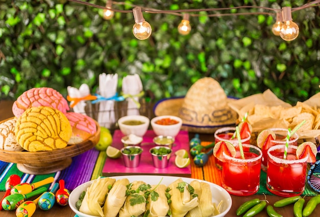 Foto tavolo da festa con tamales, margarita alla fragola e pan dulche.