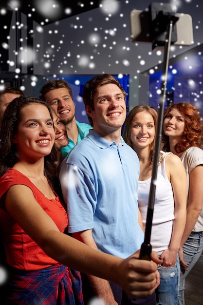 party, technology, nightlife and people concept - smiling friends with  smartphone taking selfie in club. Stock Photo