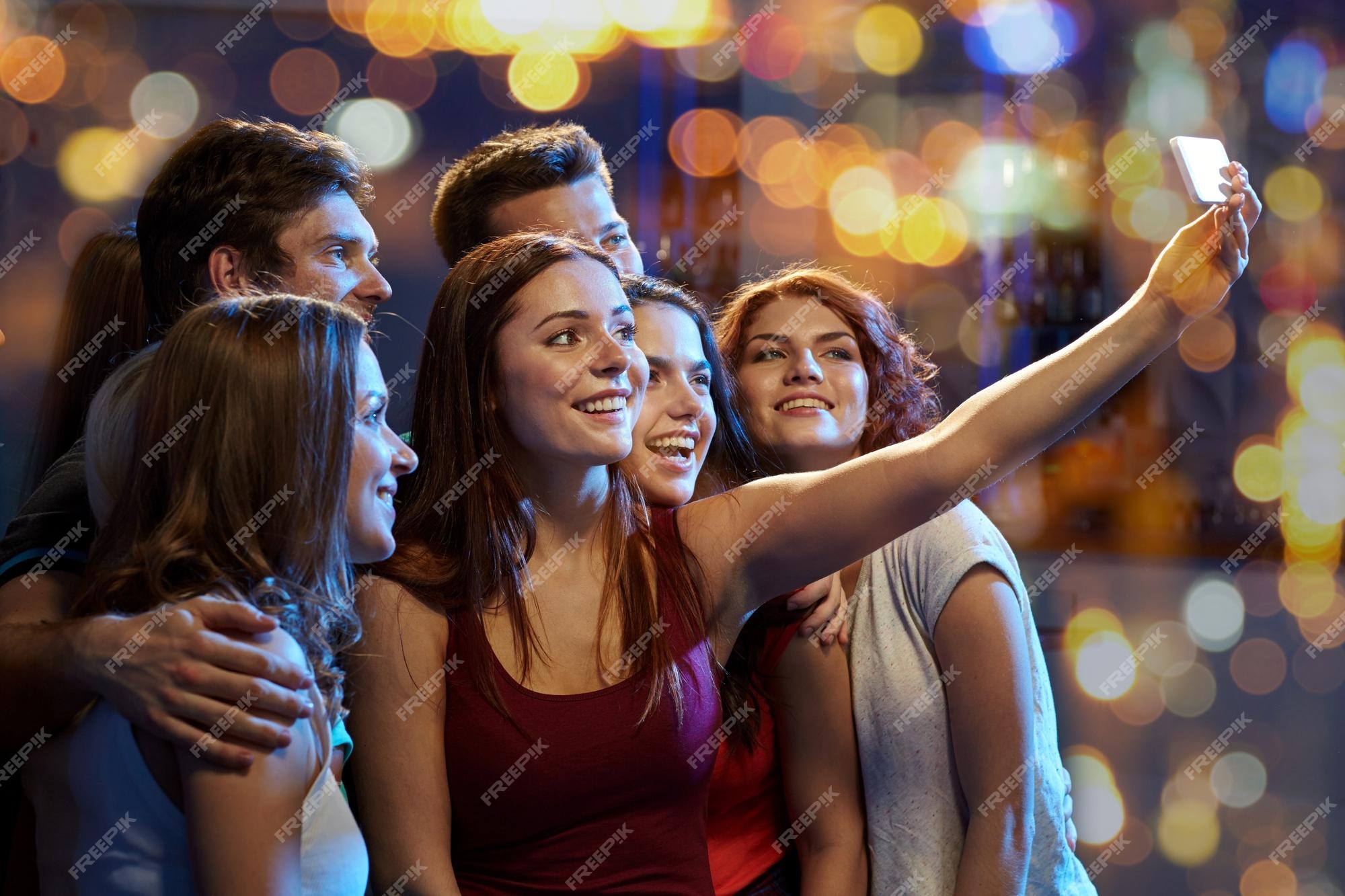 party, technology, nightlife and people concept - smiling friends with  smartphone taking selfie in club. Stock Photo