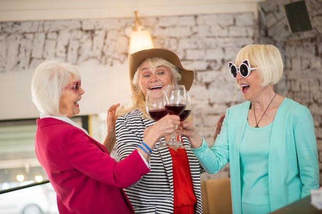 パーティー。パーティーを開き、ワインを飲みながら楽しんでいる3人のシニア幸せな女性