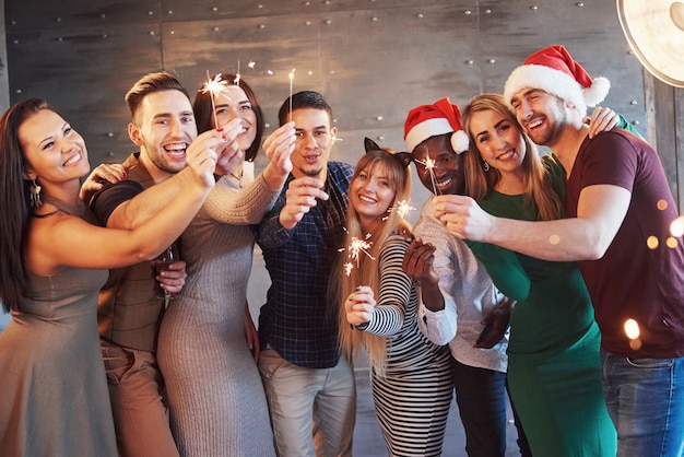 Photo party with friends. group of cheerful young people carrying sparklers and champagne flutes