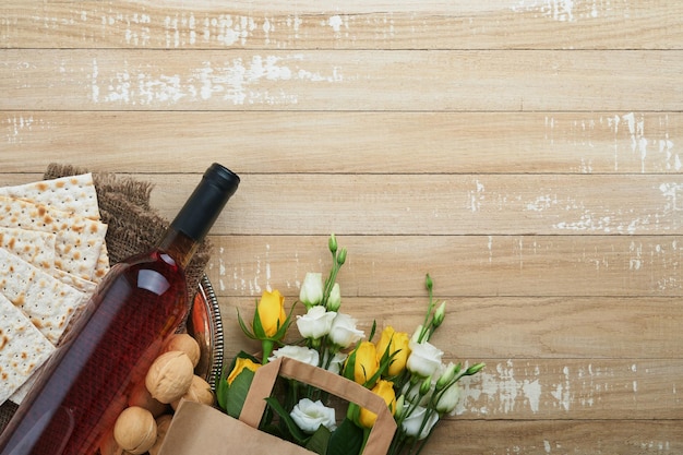 Pascha Pesah viering concept Matzah koosjere rode wijn walnoot en witte en gele rozen Traditioneel ritueel Joods brood op zand kleur oude tegel muur achtergrond Pesach Joodse feestdag Bovenaanzicht