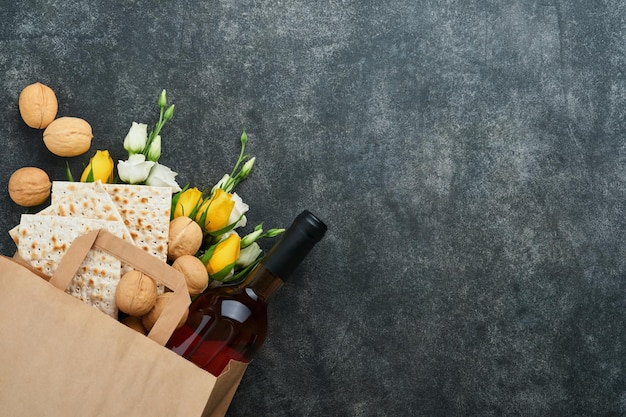 Pascha Pesah viering concept Matzah koosjere rode wijn walnoot en witte en gele rozen Traditioneel ritueel Joods brood op zand kleur oude tegel muur achtergrond Pesach Joodse feestdag Bovenaanzicht