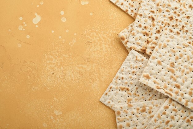 Pascha Pesah viering concept Matzah koosjere rode wijn walnoot en witte en gele rozen Traditioneel ritueel Joods brood op zand kleur oude tegel muur achtergrond Pesach Joodse feestdag Bovenaanzicht