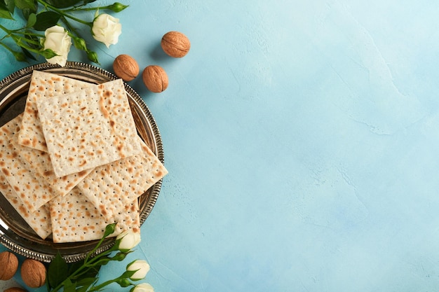 Pascha viering concept Matzah rode koosjer walnoot en lente mooie roze bloemen Traditioneel ritueel Joods brood op licht turquoise of blauwe achtergrond Pascha eten Pesach Joodse feestdag