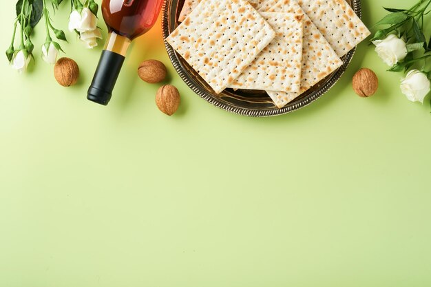 Pascha viering concept Matzah rode koosjere wijn walnoot en lente mooie roze bloemen Traditioneel ritueel Joods brood op lichtgroene achtergrond Pascha eten Pesach Joodse feestdag