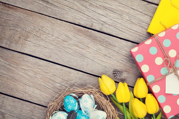 Pasen-achtergrond met blauwe en witte eieren in gele tulpen en geschenkdoos