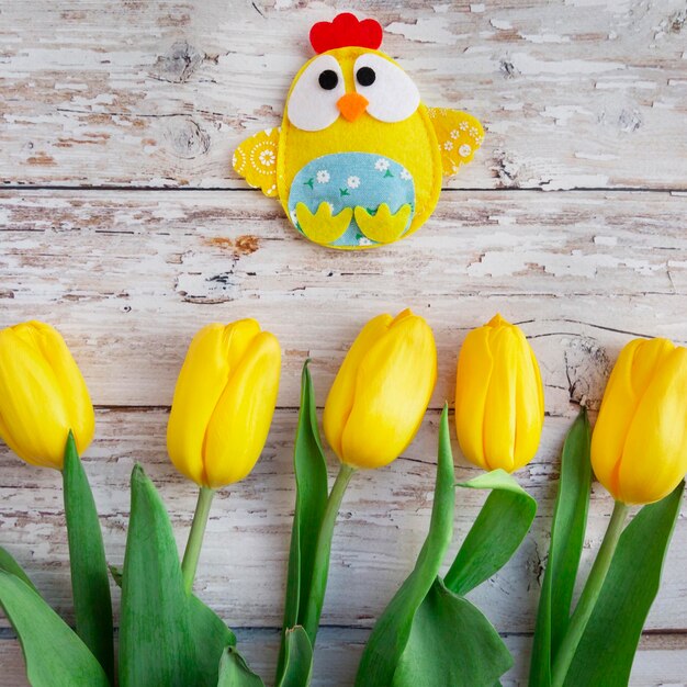 Pasen achtergrond met decoratieve chick en gele tulpen op houten achtergrond