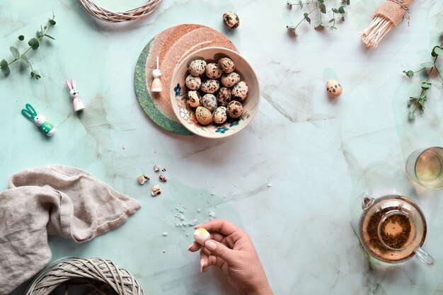 Pasen-achtergrond op muntgroene marmeren lijst. kwartel paaseieren en natuurlijke lentedecoraties en eucalyptustakjes. groene thee in glazen theepot.