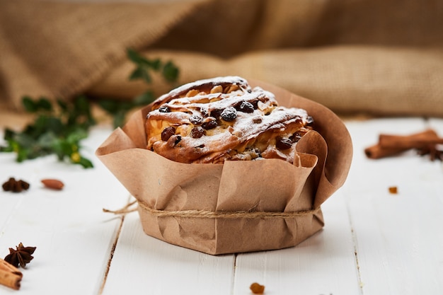 Pasen-cake door rozijnen en suikerglazuursuiker wordt verfraaid op witte houten achtergrond, traditionele kulich, paska klaar voor viering die