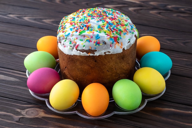 Pasen-cake en geschilderde kleurrijke eieren op donkere houten raad.