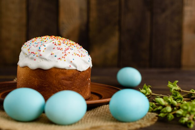 Pasen-cake en kleurrijke eieren op een houten lijst.