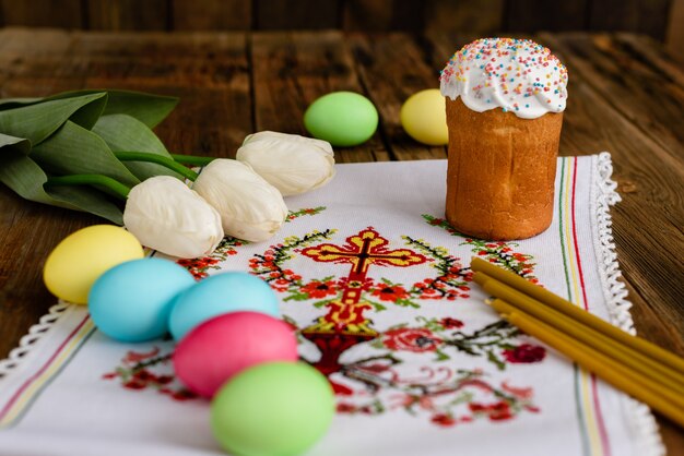 Pasen-cake en kleurrijke eieren op een houten lijst.