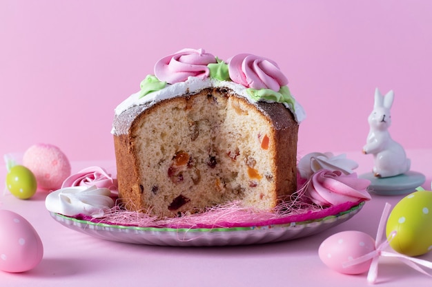 Pasen cake in gesneden op roze achtergrond met kleurrijke eieren.