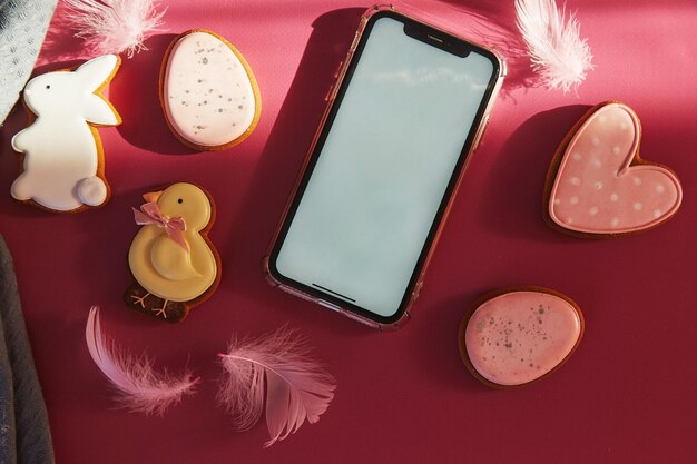 Pasen-esthetiekkoekjes en mock-up van schermtelefoon op Viva Magenta-achtergrond onder de schaduwen plat lag Happy Easter