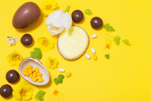 Pasen gele achtergrond met chocolatte eieren, snoep en spri