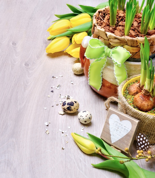 Pasen-grens met gele tulpen en natuurlijke decoratie op hout