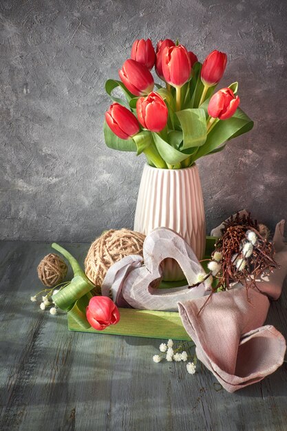 Pasen-het ontwerp van de groetkaart met bos van rode tulpen op plattelander met Pasen-decoratie, copyspace