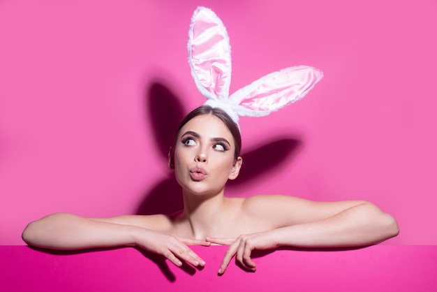 Pasen jonge vrouw studio dragen bunny oren nieuwsgierig geïsoleerd op roze