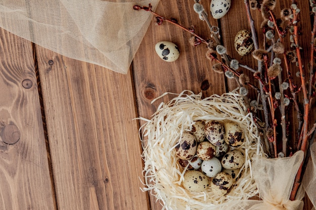 Pasen-kwartelseieren in nest en wilgentak op een houten achtergrond, exemplaarruimte