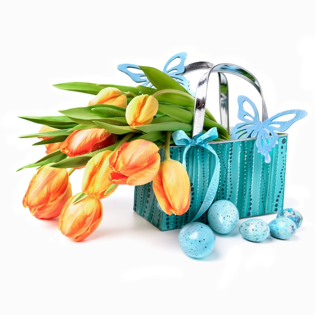 Pasen-mand met tulpen, eieren en houten vlinders op wit