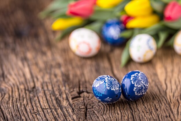 Pasen. Met de hand gemaakte paaseieren en lentetulpen op oude houten tafel.