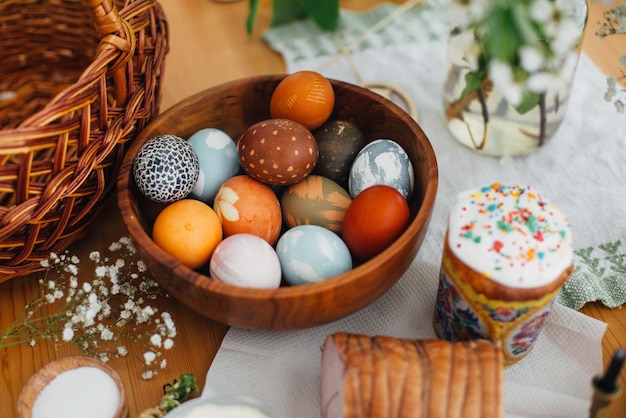 Pasen moderne eieren paascake ham groene takken en bloemen op rustieke houten tafel met rieten mand en kaars Vakantie voorbereidingen Traditioneel Pasen Voedsel voor ontbijt