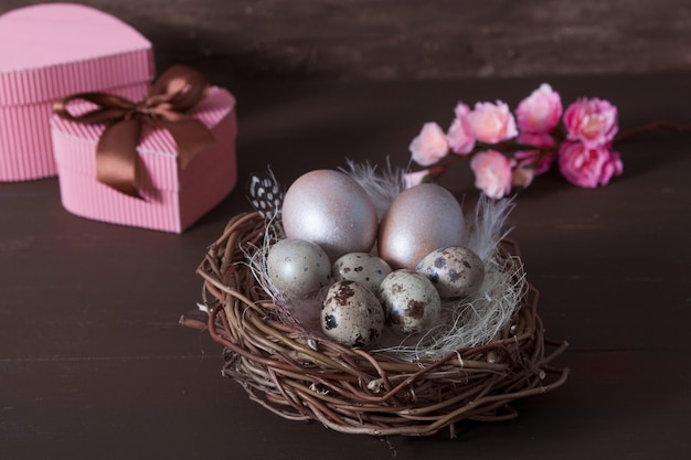 Pasen-nest met eieren op bruine bakcground met roze bloesembloemen en giftdozen