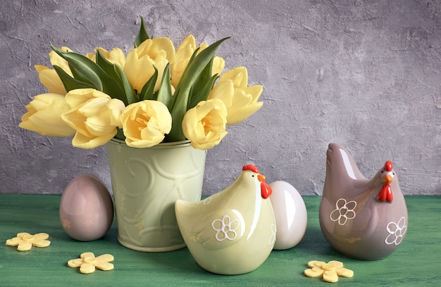 Pasen-samenstelling met gele tulpen, ceramische kippen en paaseieren