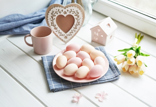 Pasen-samenstelling met gele tulpen en roze eieren