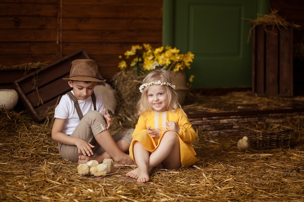 Pasen! Schattige kleine gelukkige kinderen, een jongen en een meisje in het hooi met dieren - kippen en een konijn op Paasdag.