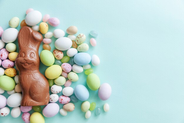 Pasen snoep chocolade eieren konijn en jellybean snoepjes geïsoleerd op blauwe tafel