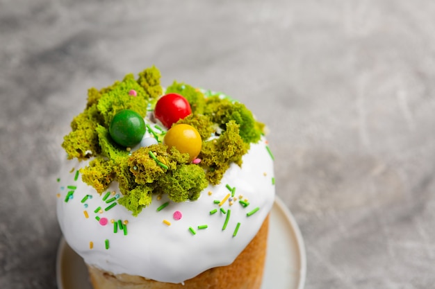 Pasen taart kulich. Traditioneel zoet paasbrood versierd meringue en verschillende snoepeieren op plaat op grijze stenen tafelachtergrond. Ruimte kopiëren.