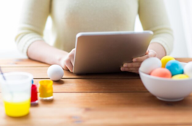 pasen, vakantie, technologie en mensenconcept - close-up van vrouwenhanden met tablet pc-computer, paaseieren en kleuren