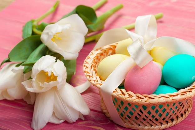 Pasen, vakantie, traditie en object close-up van gekleurde eieren en tulpenbloemen over houten planken