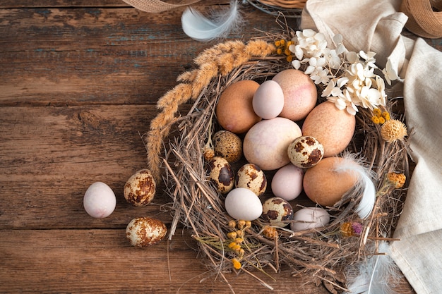 Pasen vintage achtergrond. Kwarteleitjes en kippeneieren liggen in een rieten nest, versierd met bloemen