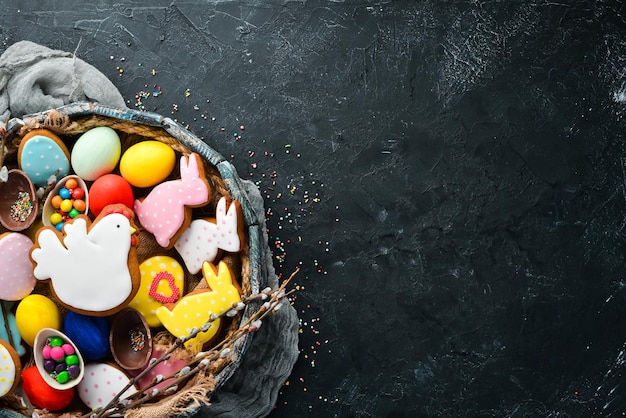 Pasen-wenskaart Vrolijk Pasen Pasen-peperkoekkoekjes en decoratieve gekleurde eieren Op een zwarte achtergrond Bovenaanzicht Gratis kopieerruimte