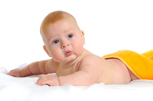 Pasgeboren baby bedekt met een gele handdoek die in bed ligt