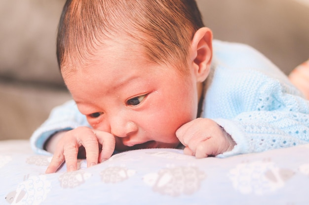 Pasgeboren baby die met zijn gezicht naar beneden in zijn kussen bijt