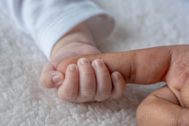 Pasgeboren baby die moeders vinger vasthoudt