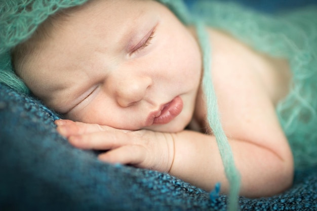 Pasgeboren baby die zoet slaapt op een blauw kleed met blauwe muts