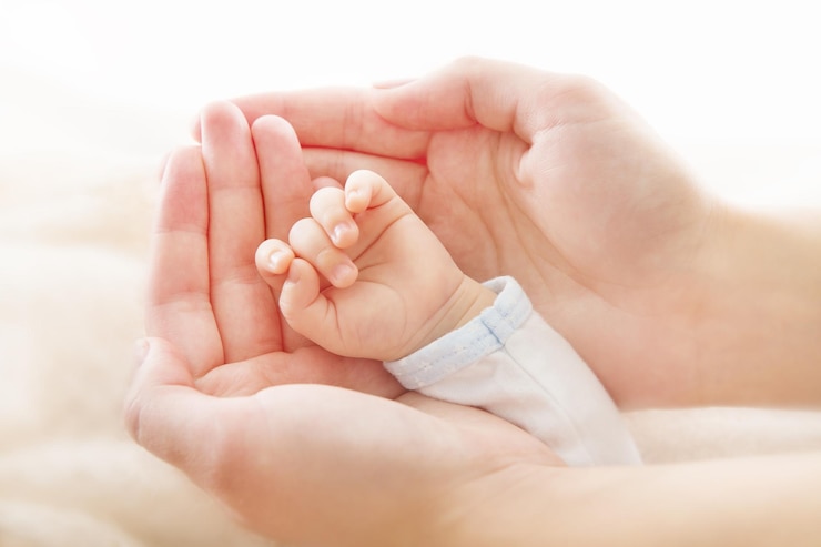 Foto pasgeboren baby hand in hand met moeder