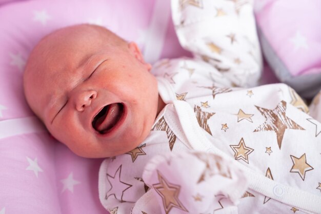 Pasgeboren baby huilt in de wieg Nieuwgeboren kind moe en hongerig in bed Kind huilt thuis