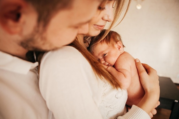 Pasgeboren baby in de armen van jonge ouders